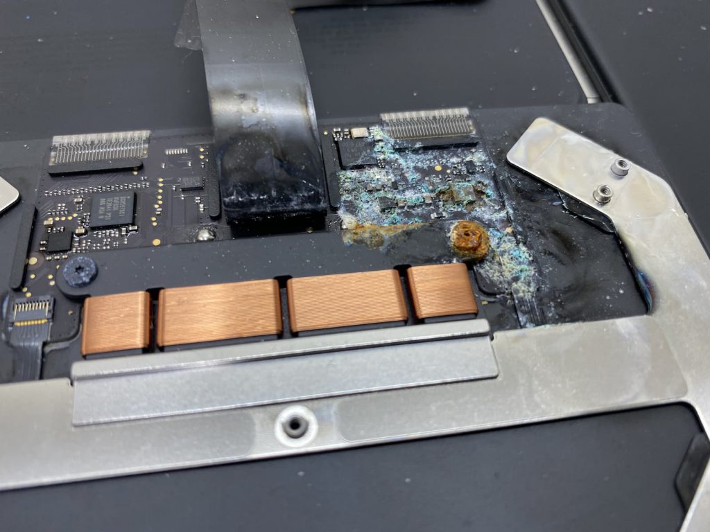 Closeup of MacBook Air trackpad with heavy corrosion due to liquid damage.